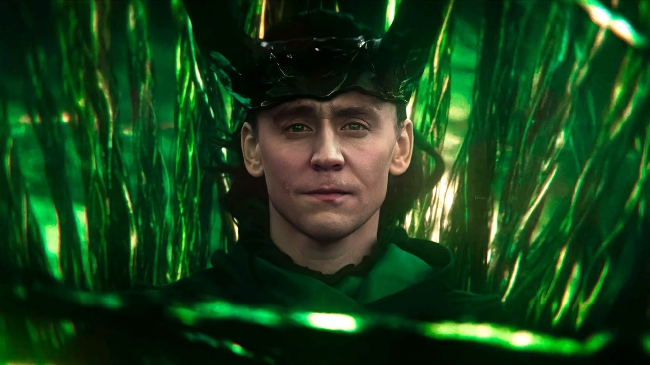 Loki sits at the centre of Yggdrasil, framed symmetrically by towering green branches that close in on either side of his face.